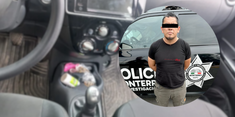Suspect standing in front of a police vehicle with a star badge visible on the side; eyes covered with a black bar and wearing a black t‑shirt.