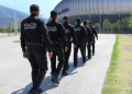 Monterrey police officers walking in formation along a walkway beside a large stadium.