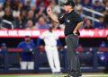 MLB umpire signaling a call on a play during a baseball game, with players and crowd in the background