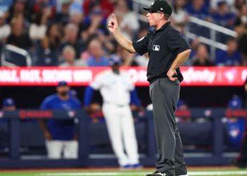 MLB umpire signaling a call on a play during a baseball game, with players and crowd in the background