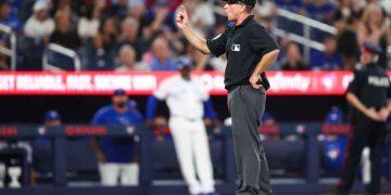 MLB umpire signaling a call on a play during a baseball game, with players and crowd in the background