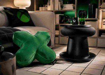 Cozy living room corner with a green X-shaped cushion, a black round coffee table, and an Xbox mug on a tray.